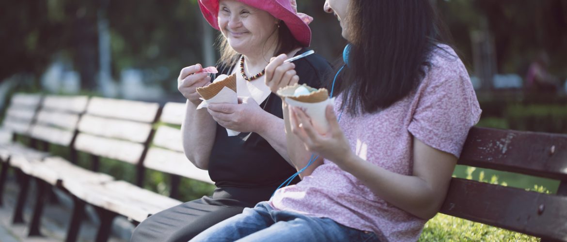 Woman with Down Syndrome and her assistant eating ice cream and having fun
