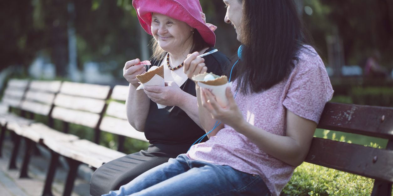 Woman with Down Syndrome and her assistant eating ice cream and having fun