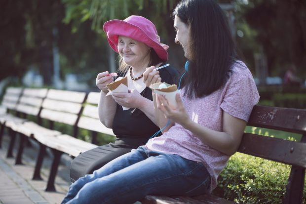Woman with Down Syndrome and her assistant eating ice cream and having fun