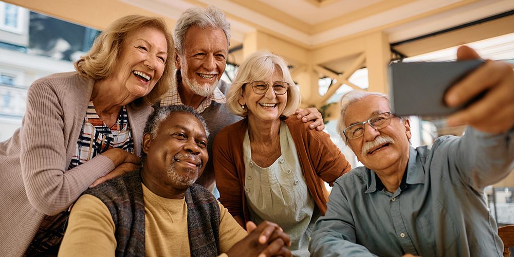 Cheerful senior having fun while taking selfie at retirement community.