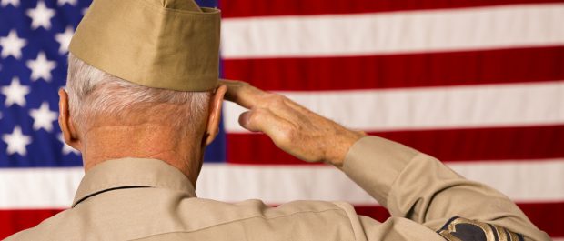 Military: Senior veteran in uniform saluting American flag.