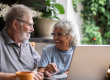 Elderly couple at table looking at laptop