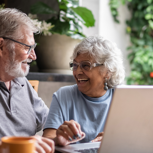 Elderly couple at table looking at laptop