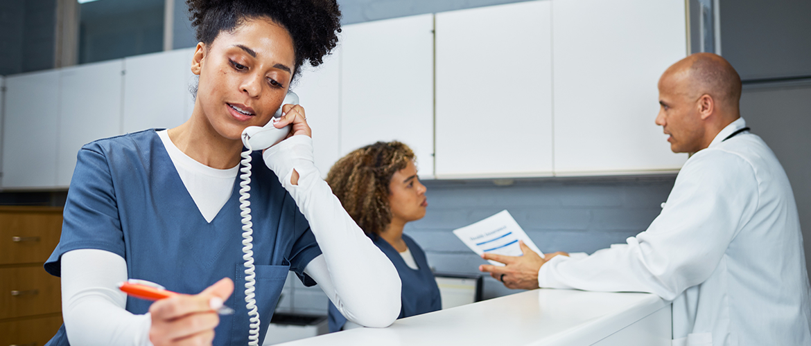 Nurse on phone while doctor and other nurse talk behind her.