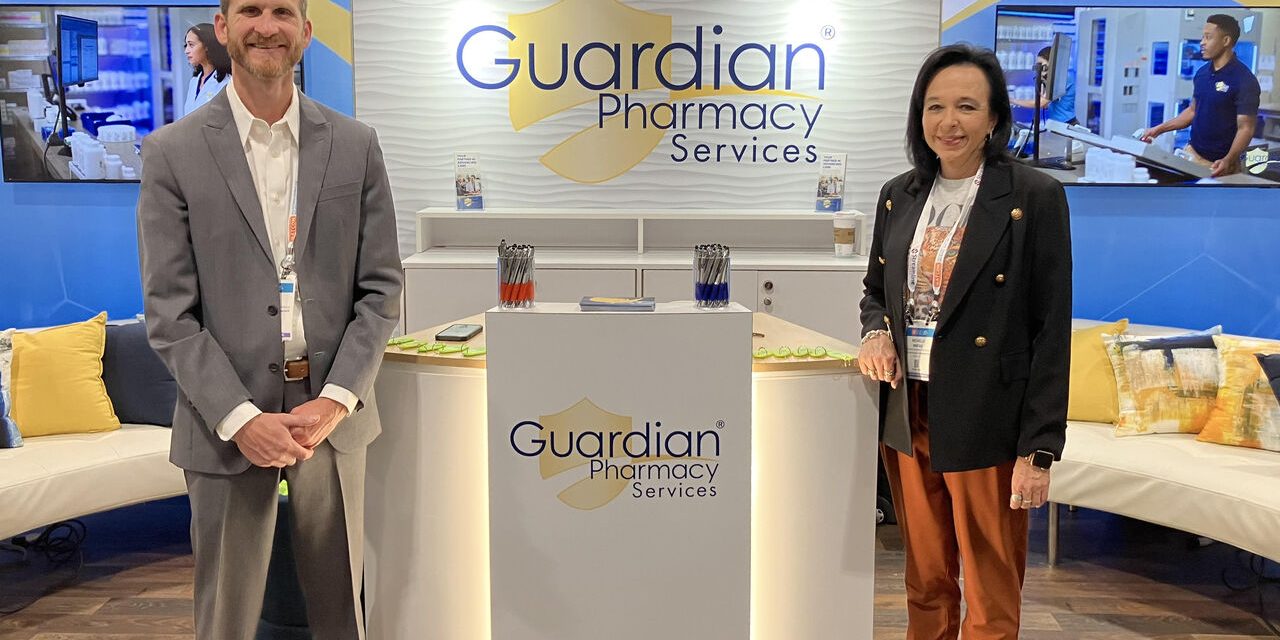 Two people standing at a Guardian Pharmacy podium