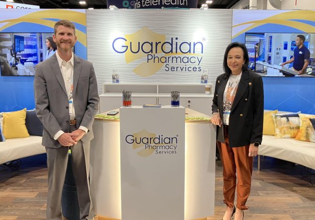 Two people standing at a Guardian Pharmacy podium