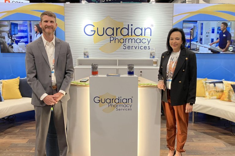 Two people standing at a Guardian Pharmacy podium