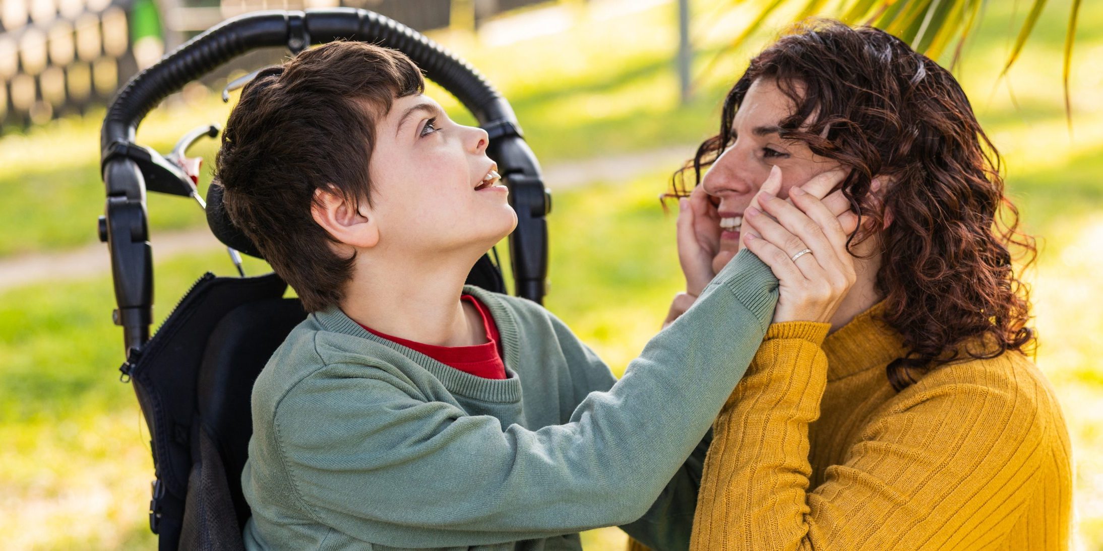 child in wheelchair playing with mother in park