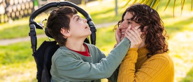 child in wheelchair playing with mother in park