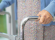 Elderly person grips a chrome walker to support walking and balance.